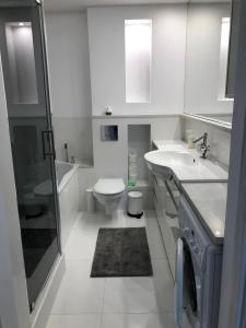 a white bathroom with a toilet and a sink at Apartamenty Bałtyckie - Wczasowa - osiedle zamknięte, winda, miejsce parkingowe in Ustka