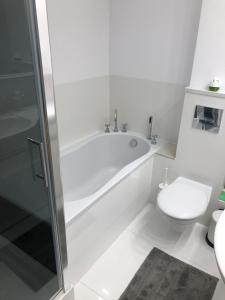 a white bathroom with a tub and a toilet at Apartamenty Bałtyckie - Wczasowa - osiedle zamknięte, winda, miejsce parkingowe in Ustka