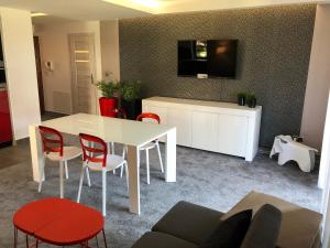 sala de estar con mesa blanca y sillas rojas en Apartamenty Bałtyckie - Wczasowa - osiedle zamknięte, winda, miejsce parkingowe, en Ustka