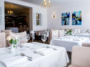 ein Restaurant mit weißen Tischen und Stühlen mit weißen Tischdecken in der Unterkunft Hotel Koloseum in Turek