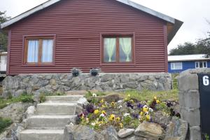 a house with a stone wall and flowers in front of it at Cabañas "Las Margaritas" in Ushuaia