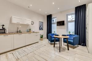 a kitchen and living room with blue chairs and a table at KATO Apartamenty Słowackiego in Katowice