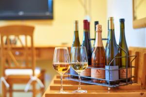 two glasses of wine on a table with wine bottles at Gästehaus Achenbach in Wonsheim