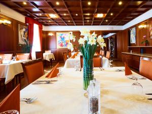 a dining room with a table with flowers in a vase at Hradná stráž Hotel&Apartments s privátnym wellness in Topoľčianky