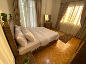 una camera da letto con letto, lenzuola e cuscini bianchi di Maspero Nile View Serviced Apartments by Brassbell a Il Cairo