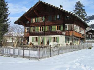 a wooden house with a fence in the snow at Chalet Halten in Lenk