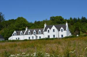 a large white house sitting on top of a hill at The Inn @ Aird a' Bhasair in Ardvasar