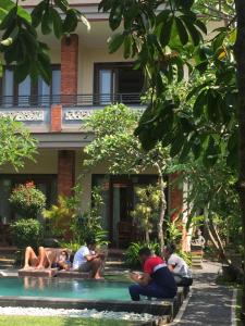 a group of people sitting around a swimming pool at Umah Dangin Guest House in Ubud