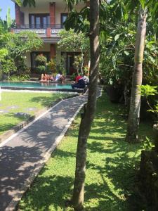 a group of people laying on the grass by a swimming pool at Umah Dangin Guest House in Ubud