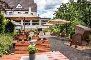 een groep tafels en stoelen met parasols bij Bielefelder Berghotel zum Stillen Frieden in Bielefeld