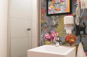 a bathroom with a sink and a flower wallpaper at Mary-Ann's Polarrigg in Longyearbyen