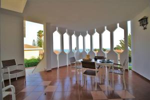 comedor con mesa, sillas y ventanas en Villa Anastasia, en Fontane Bianche