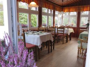 uma sala de jantar com mesas, cadeiras e janelas em Theeshof em Soltau