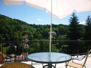 een tafel en stoelen op een balkon met een parasol bij Hotel Waldhaus-Hutzelhöh in Ruhla