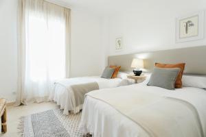 two beds in a white room with a window at Reformed and bright- 2Bdr 1Bth- Nervion in Seville