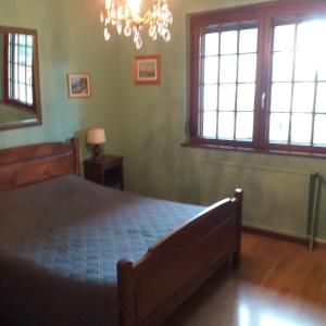 a bedroom with a bed and two windows and a chandelier at B&B Ma Maison Hautes Vosges in Ranspach