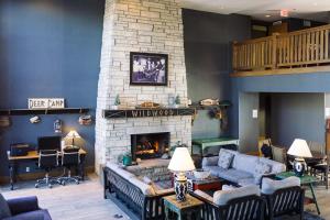 Wildwood Lodge & Suites في Clive: غرفة معيشة مع أريكة ومدفأة