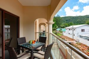 balcón con mesa, sillas y vistas en Stone Self Catering Apartment, en Grand'Anse Praslin