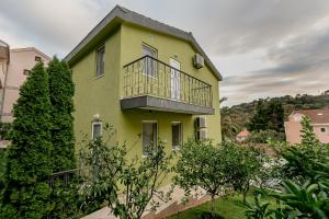 ein gelbes und grünes Haus mit einem Balkon in der Unterkunft Palm Point Apartment in Petrovac na Moru