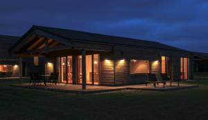 a small cabin with a porch at night at Gud Jard Lodge Nr 12 - Design-Ferienhaus mit exklusiver Ausstattung in Pellworm