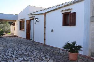 una casa blanca con una maceta delante de ella en Baglio Cracchiolo Casa Baldo en San Vito lo Capo