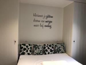 a bedroom with a bed with a quote on the wall at Merida in Knokke-Heist