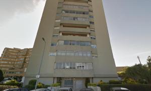 a tall building with cars parked in a parking lot at VIVA Cozy Panoramic Flat in Senhora da Hora