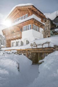 a log home in the snow with snow covered premises at Mooser Hotel in Sankt Anton am Arlberg