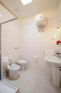 La salle de bains blanche est pourvue de toilettes et d'un lavabo. dans l'établissement Baia Di Campi, à Vieste