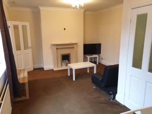 a living room with a fireplace and a table and a tv at South Shield's Hidden Gem Emerald Apartment sleeps 6 Guests in South Shields