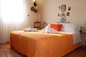 una camera da letto con un grande letto con lenzuola bianche e arancioni di Baglio Cracchiolo Casa Baldo a San Vito lo Capo