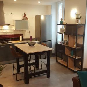 uma cozinha com uma mesa e um frigorífico de aço inoxidável em La Résidence M*C em Semur-en-Auxois