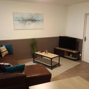 uma sala de estar com um sofá, uma mesa e uma televisão em La Résidence M*C em Semur-en-Auxois