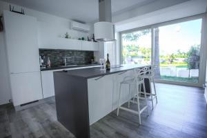 a kitchen with white cabinets and a bar with stools at T Villa in Calatabiano