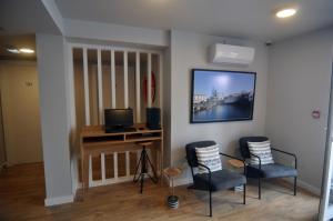 a room with two chairs and a television on a wall at Porto Velho Boutique Hostel in Madalena