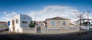 a white house with a fence in a street at Hospedaria Isaias in Angra do Heroísmo