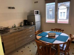 uma pequena cozinha com uma mesa e um frigorífico em Villa Coquelicot Plage em Le Tréport