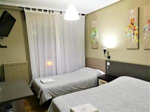um quarto de hotel com duas camas e uma mesa em Pension Santiago em Burgos