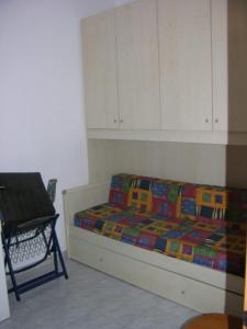a bedroom with a bed and a chair and cabinets at Villeta Laura in Baia verde in Il Monte