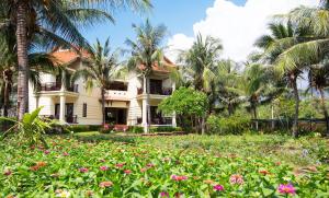 a house in the middle of a field of flowers at Golden Coast Resort & Spa in Phan Thiet