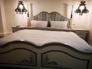 uma cama grande num quarto com 2 lustres em Stay in TimisoarAcom em Timisoara