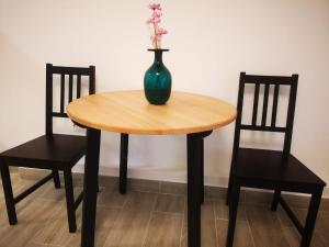 a vase sitting on a wooden table with two chairs at Stay in TimisoarAcom in Timişoara