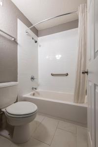 a white bathroom with a toilet and a bath tub at Hotel Monreale Express International Drive Orlando in Orlando