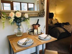 una mesa con dos platos y un jarrón con flores en Grange Farm Lodge, en Ripon