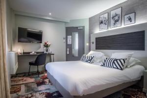 Un dormitorio con una cama blanca grande y un escritorio en Hôtel Couvent du Franciscain Centre ville, en Estrasburgo