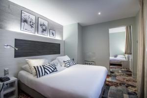 a bedroom with a large white bed with two pillows at Hôtel Couvent du Franciscain Centre ville in Strasbourg +87 photos