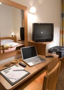 a room with a desk with a laptop and a television at Hotel Savoia in Cesenatico