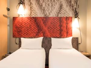 two beds in a hotel room with a headboard at ibis Bordeaux Centre - Gare Saint-Jean in Bordeaux