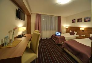 a hotel room with a bed and a desk with a laptop at Hotel Camelot in Szczawno-Zdrój