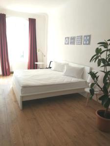 ein weißes Bett in einem Zimmer mit Topfpflanze in der Unterkunft Jules Home in Sibiu